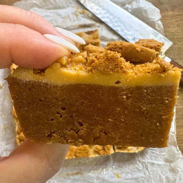Biscoff Cheesecake Slice sliced and holding